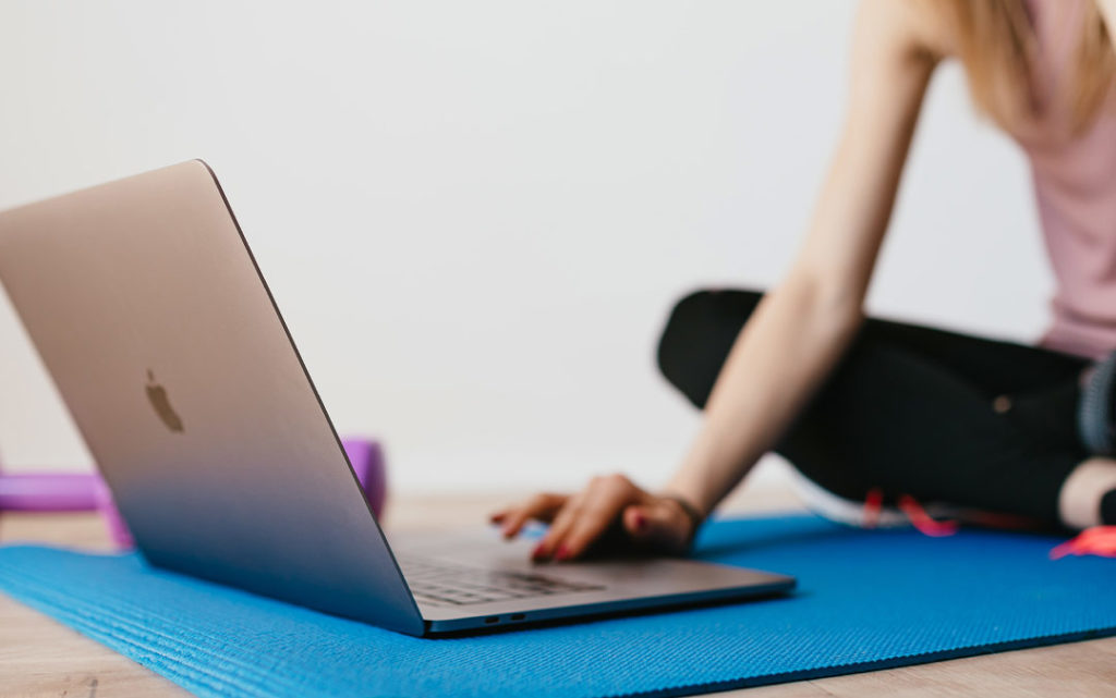 Person using a laptop on a yoga mat