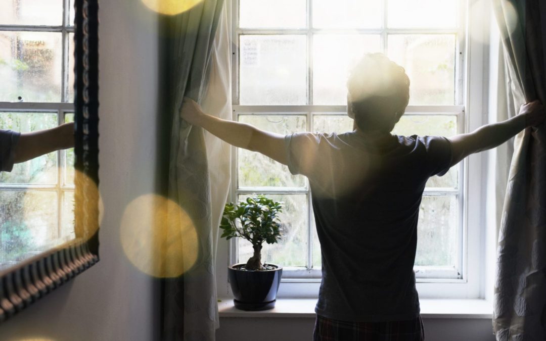 Person opening curtains on a bright sunny morning