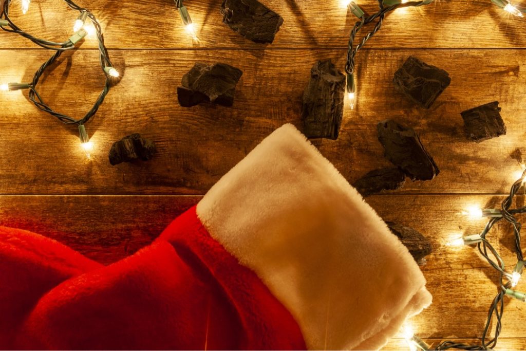 Christmas stocking on wood flooring with lumps of coal and decorative lights